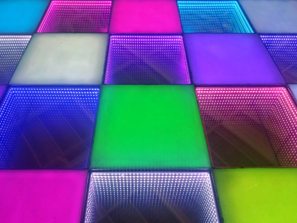 Colorful illuminated square panels in pink, blue, and green forming a geometric wall as a decorative installation.