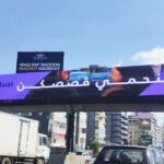 vivad jal eldib6 Purple Rock Mutual Insurance billboard on a pedestrian bridge over a busy city street.