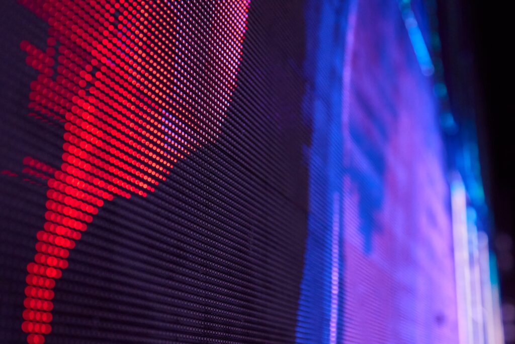 Close-up of a pixelated LED panel with red dots on the left and blue-purple glow on the right, creating a techy abstract pattern.